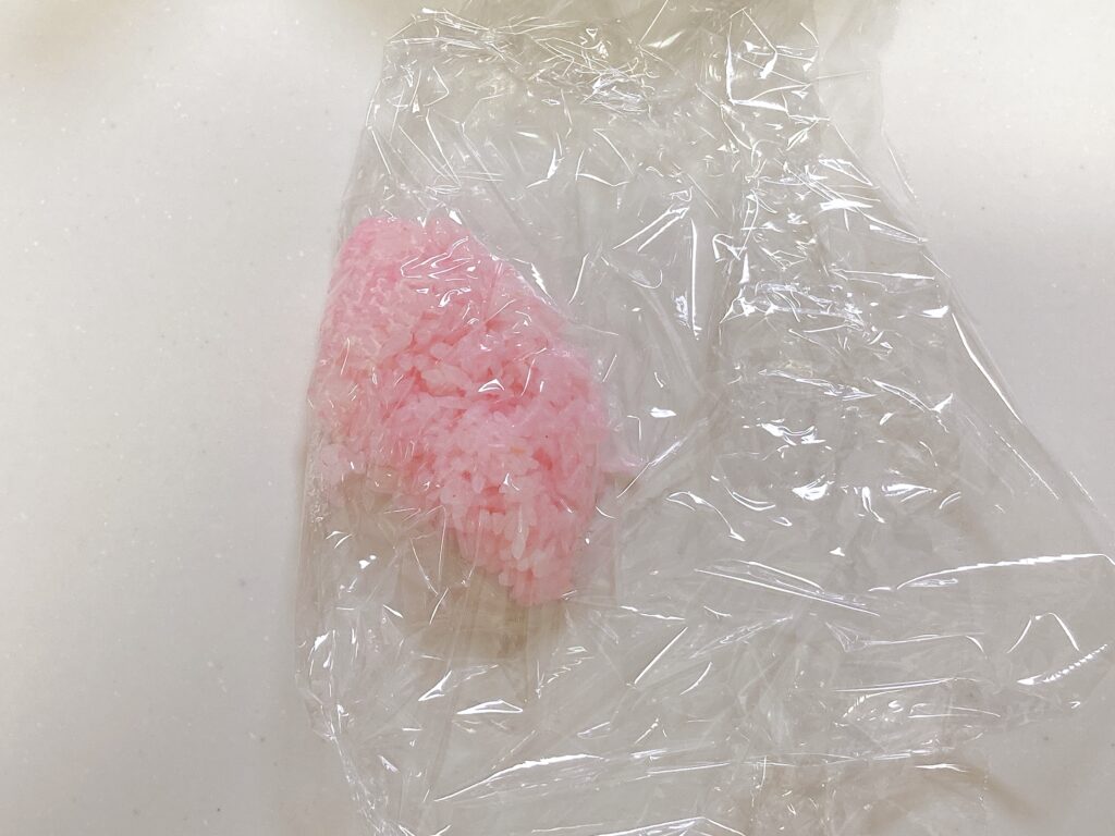 色のついたご飯をラップで包むようす